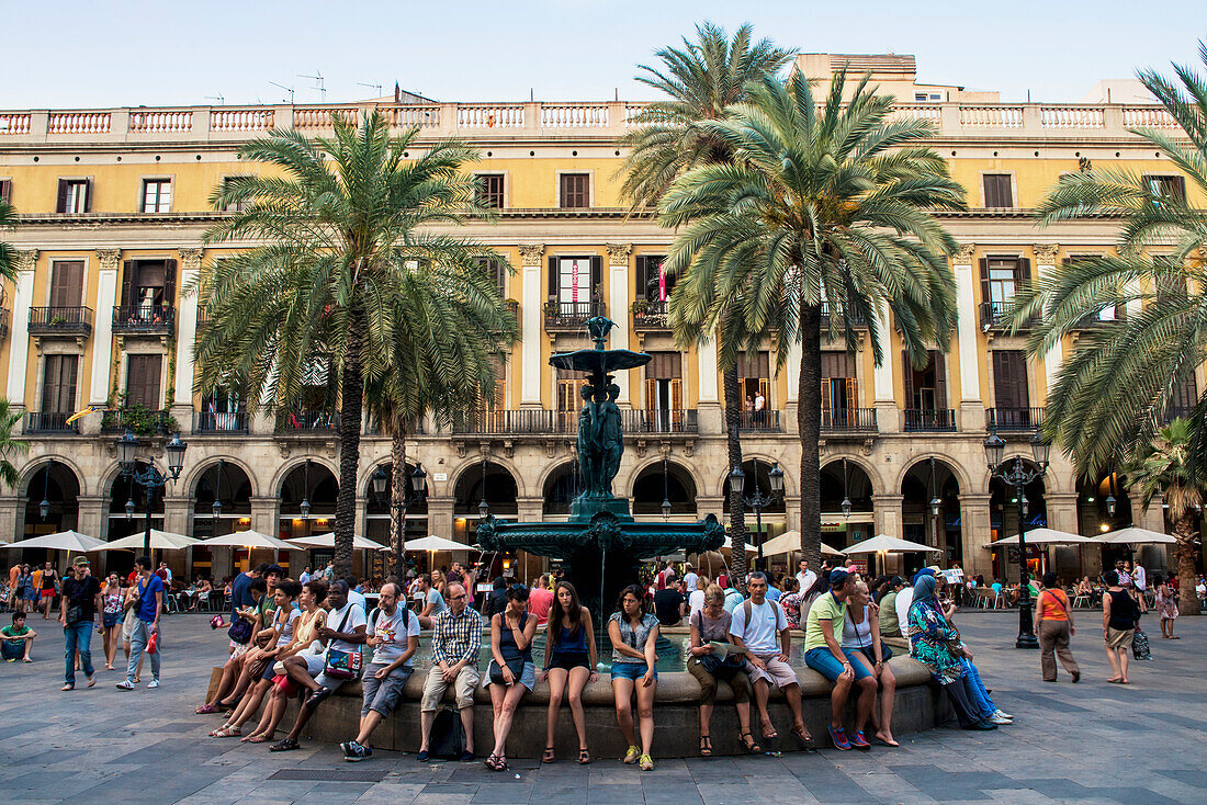 'People sitting on the edge of a water fountain at Plaza Real; Barcelona, Catalonia, Spain'