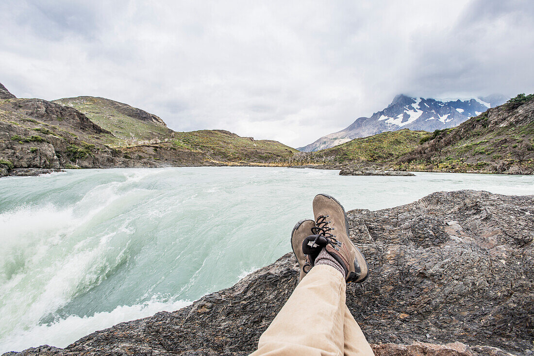 'Sitting on a rock with a view of a rushing mountain river; Tores Del Paine, Magallanes, Chile'