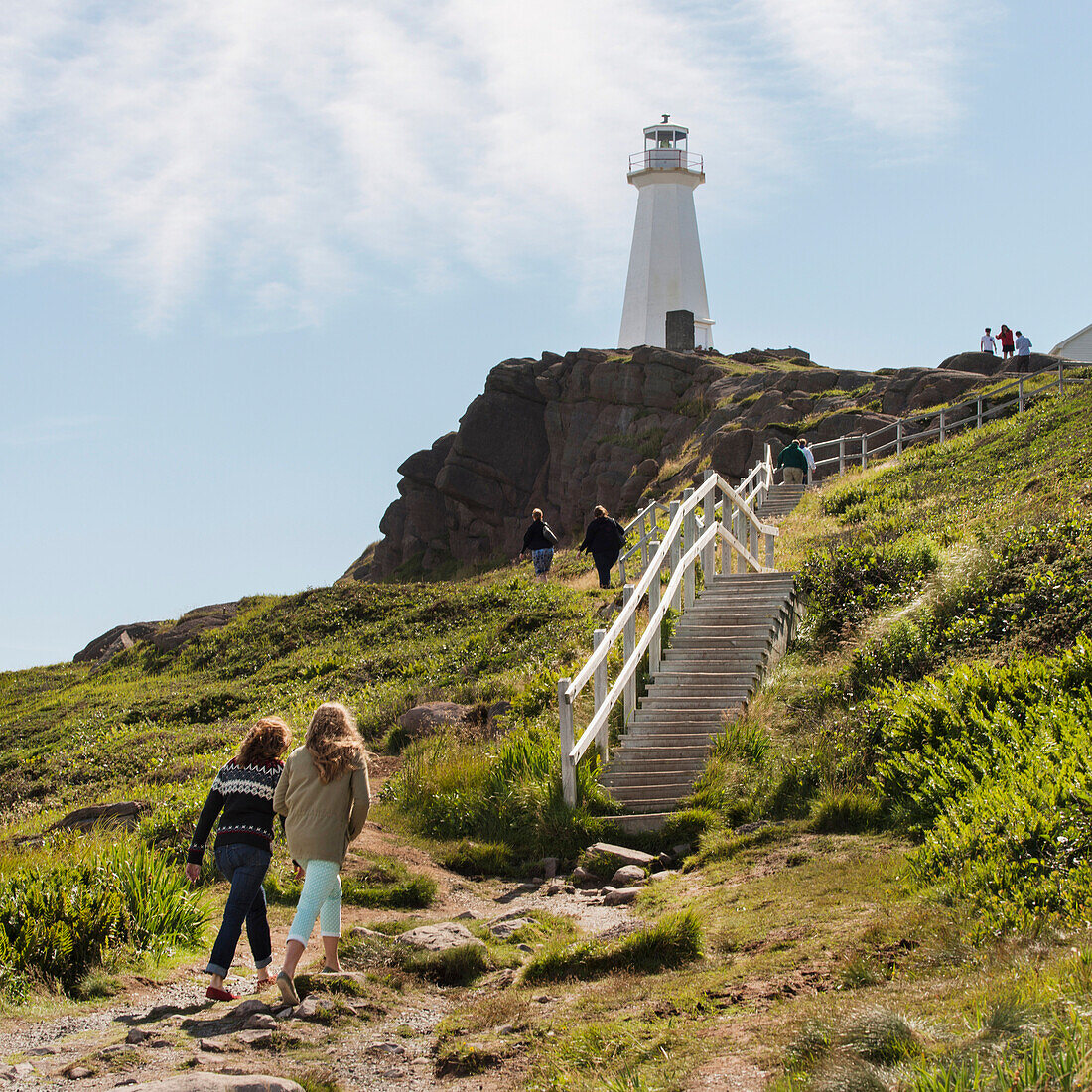 'Tourists walking to steps leading up to a lighthouse on Cape Spear; St. John's, Newfoundland and Labrador, Canada'