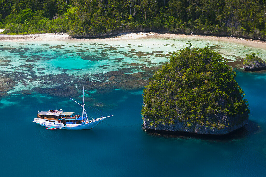 'A Bugis schooner, live-aboard dive vessel, at anchor in a limestone island lagoon; Uranie Island, Raja Ampat, West Papua, Indonesia'