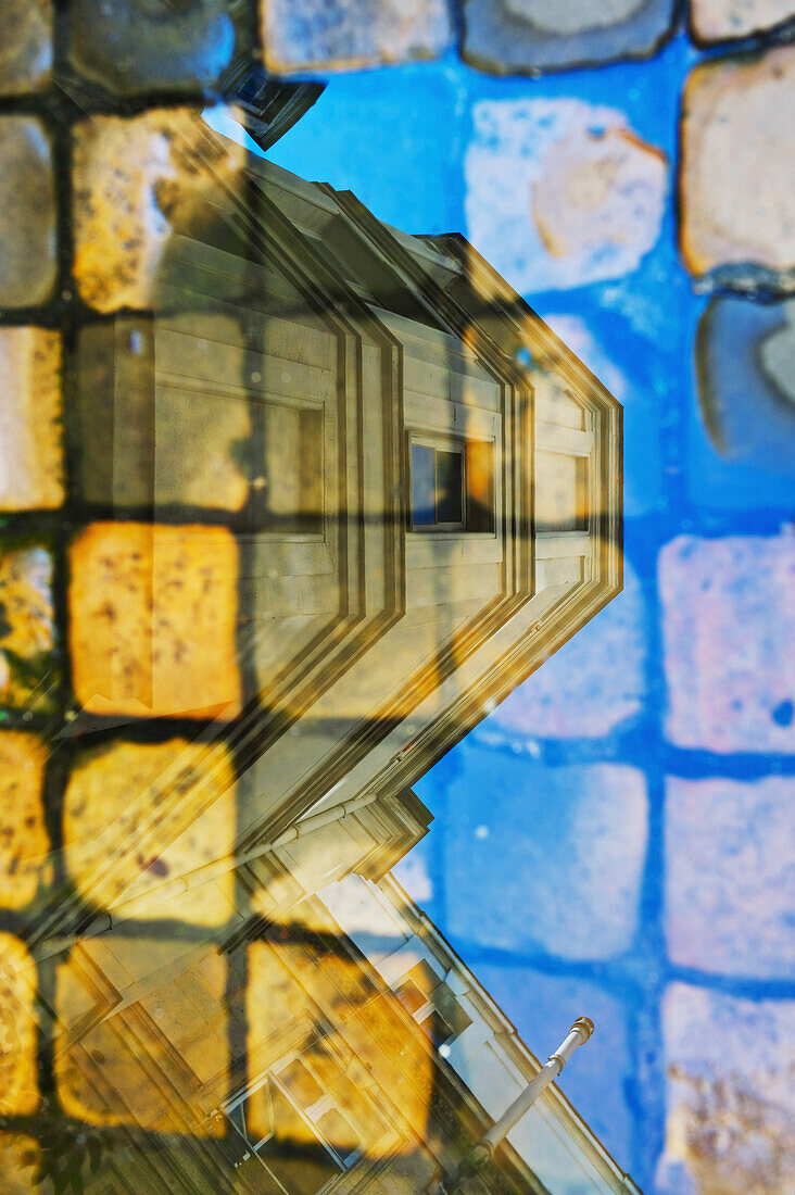 'Reflection in glass of a residential building and pavers on a walkway, Marais district; Paris, France'