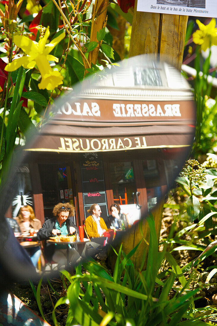 'Reflection in a car's side mirror of customer's sitting on the outdoor patio of a cafe; Paris, France'