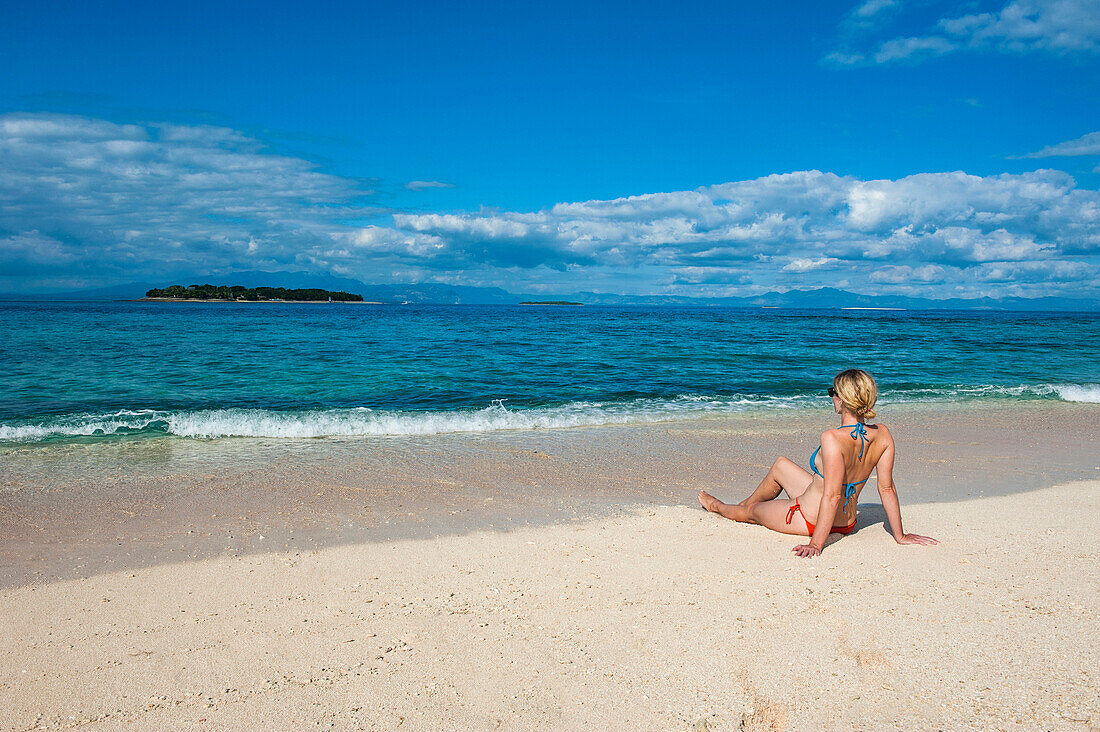 Woman sitting on a the white sand beach of Beachcomber Island, Mamanucas Islands, Fiji, South Pacific, Pacific