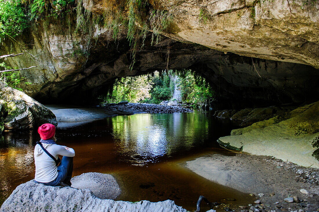 Woman enjoying the stunning Moria Gate Arch in the Oparara Basin, Karamea, West Coast, South Island, New Zealand, Pacific