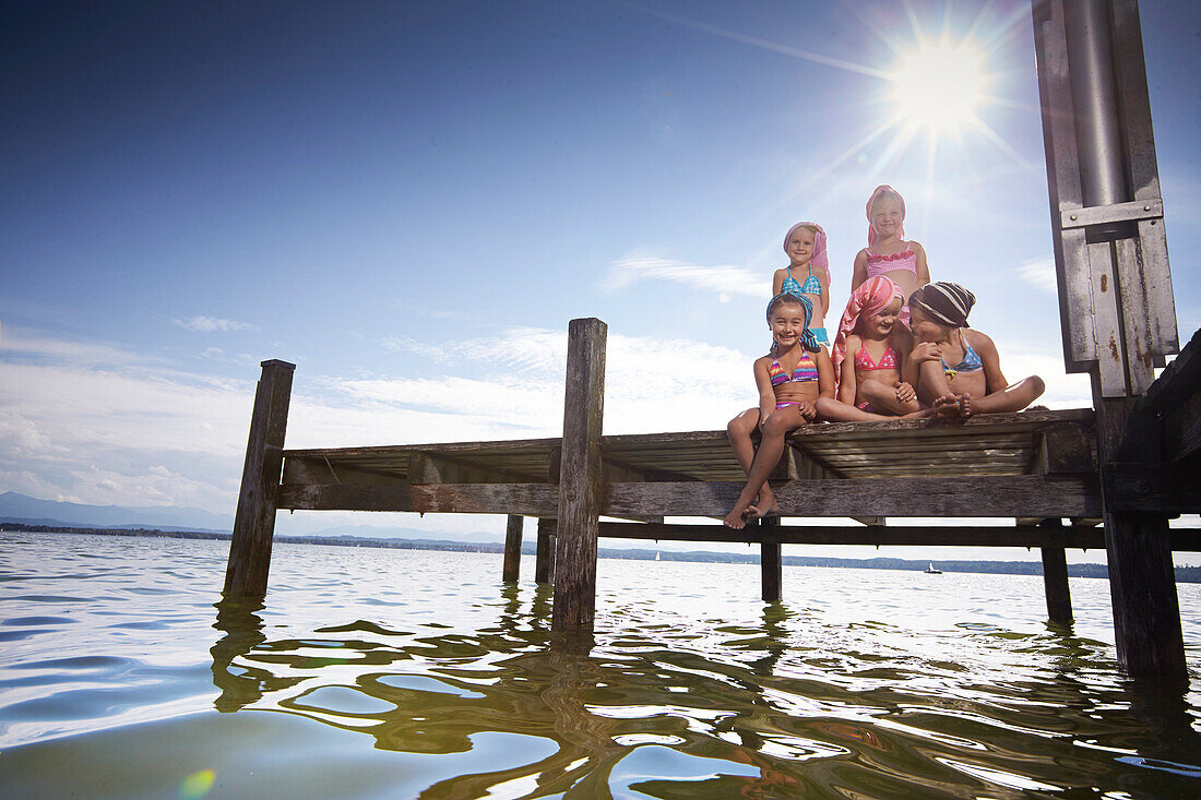 Girls sitting on a jetty, hairs wrapped in towels, lake Starnberg, Upper Bavaria, Bavaria, Germany