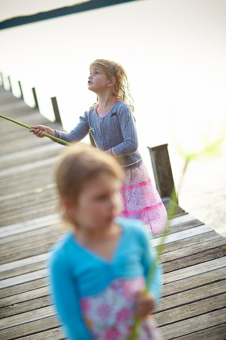 Two girls on a jetty at lake Starnberg, Upper Bavaria, Bavaria, Germany