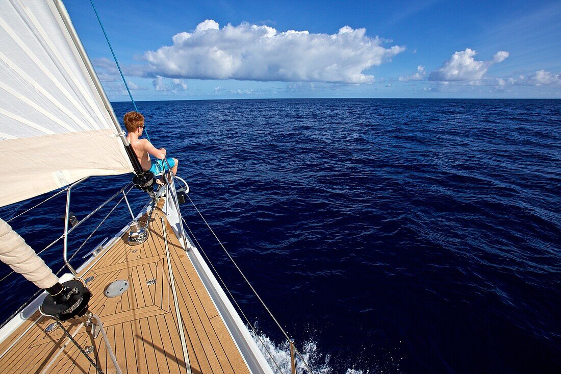 Segler sitzt am Bug einer Segelyacht in der Karibik