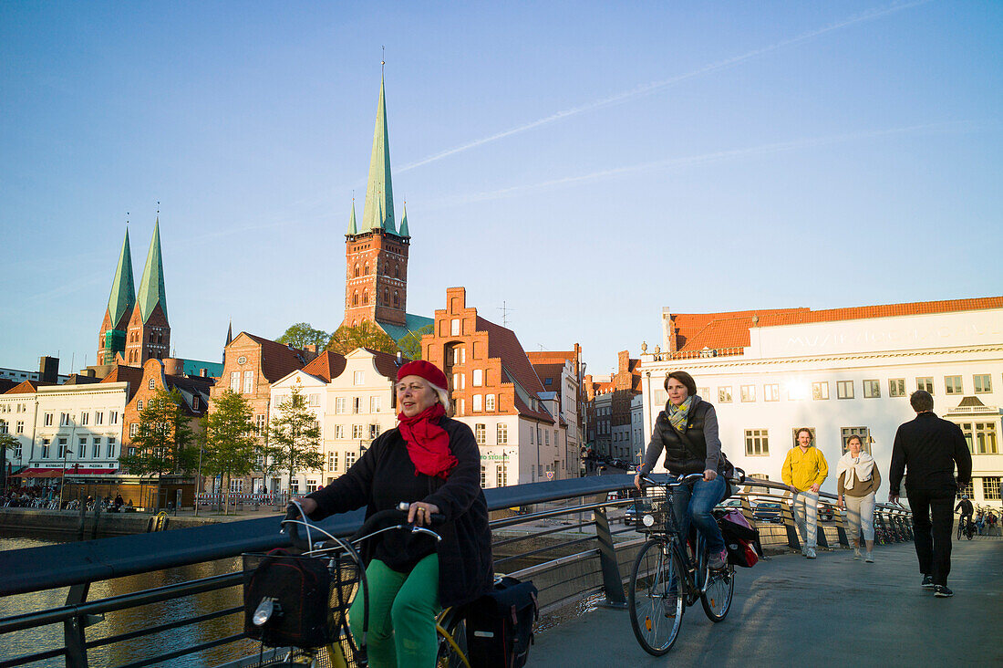 Pedestrian bridge crossing river Trave, conservatory and churches of St. Peter and St. Mary in background, historic city, Lubeck, Schleswig-Holstein, Germany