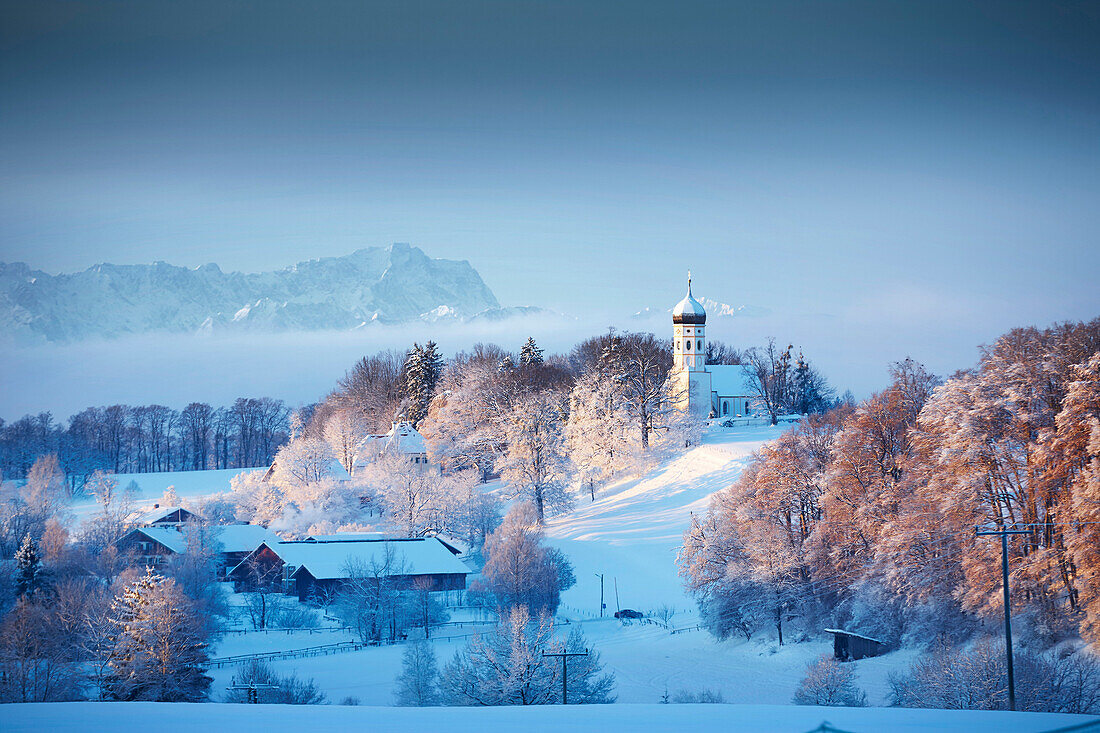 Blick auf Holzhausen mit Pfarrkirche St. Johann Baptist im Winter, Wettersteingebirge mit Zugspitze, Holzhausen, Münsing, Oberbayern, Bayern, Deutschland