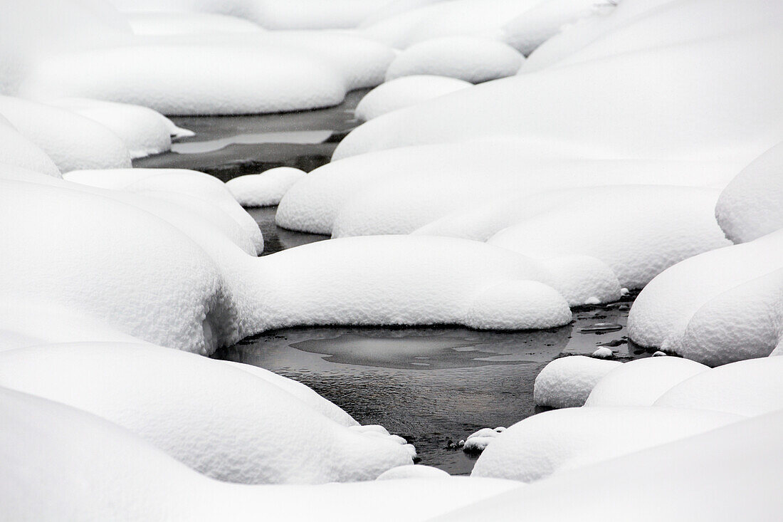 'Mounds of snow with openings showing water; Banff, Alberta, Canada'