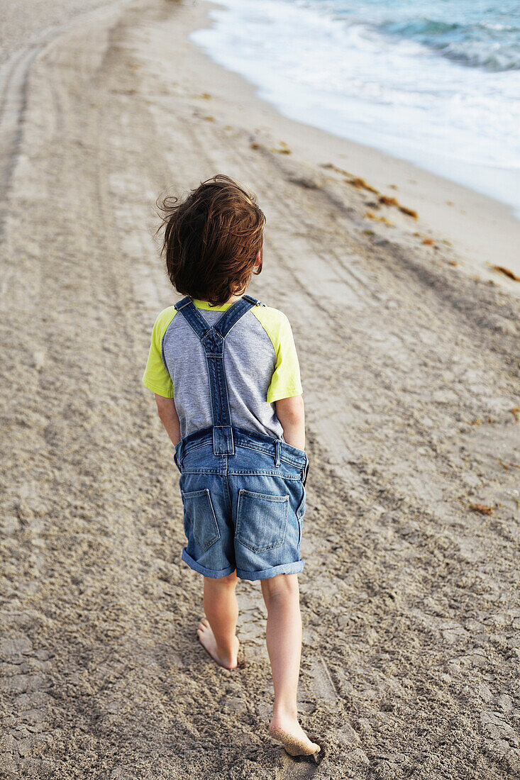 'Young boy walking on the beach; Hollywood, Florida, United States of America'
