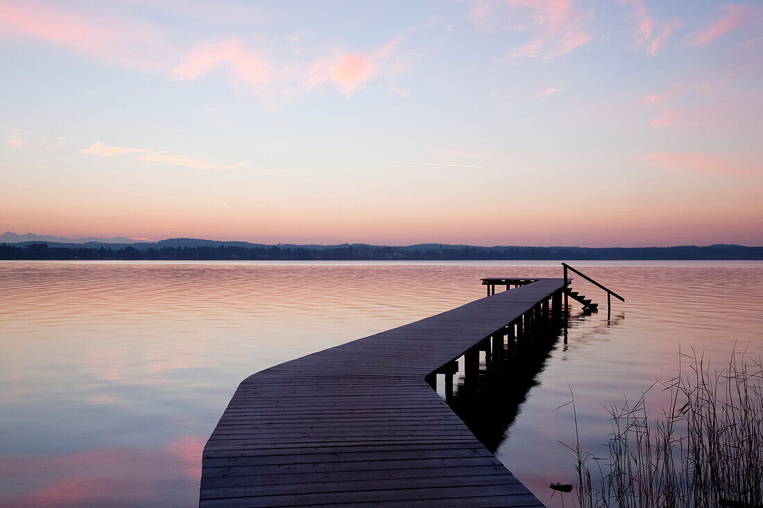 'Wooden dock leading out to the water at sunset; Starnberger See, Bavaria, Germany'