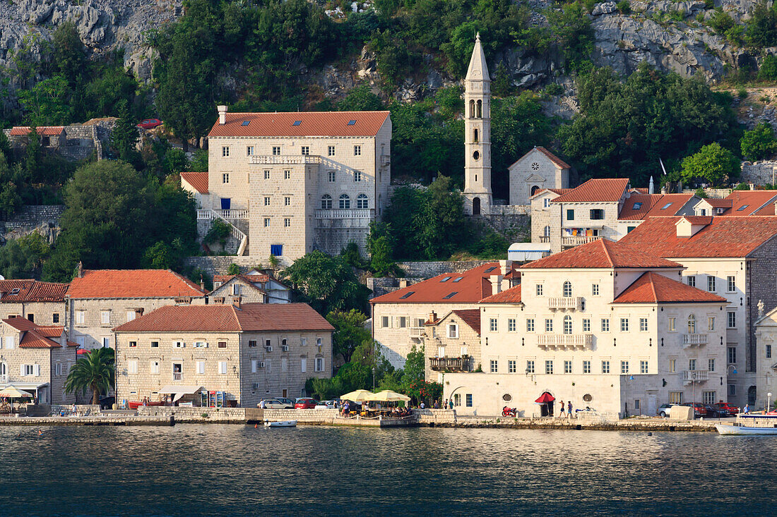 Church of Our Lady of the Rosary and a waterside restaurant lit by evening light, Perast, Bay of Kotor, UNESCO World Heritage Site, Montenegro, Europe