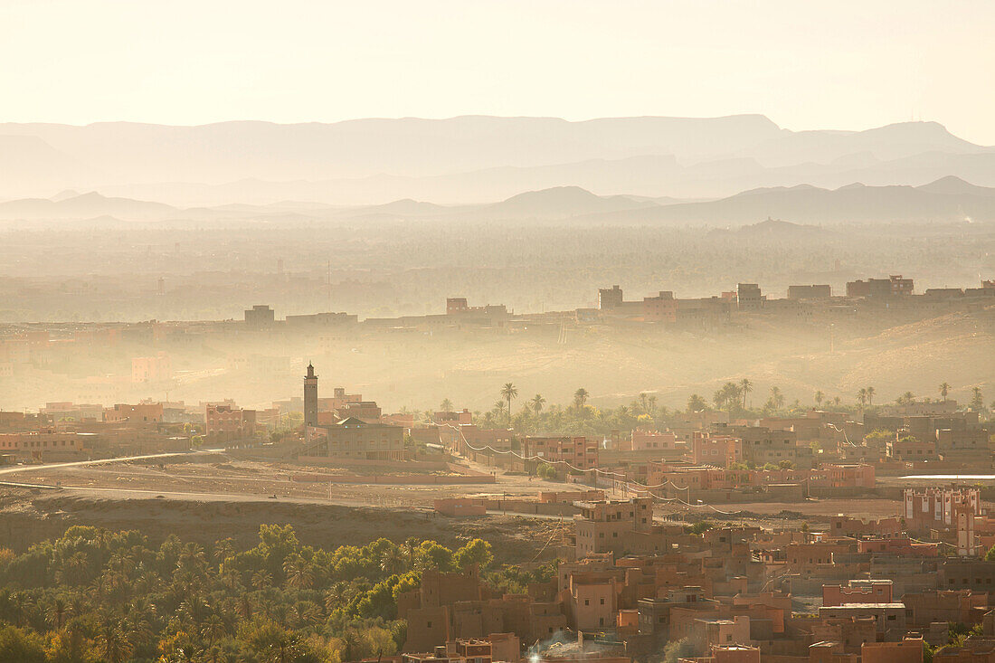 View over the town of Tinerhir soon after sunrise showing smoke rising from the streets and traditional houses bathed in sunlight, Tinerhir, Sousse-Massa-Draa, Morocco, North Africa, Africa