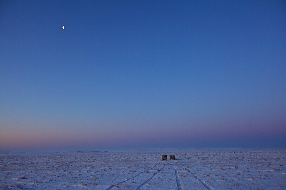 zwei UAZ-Busse in der mongolischen Steppe im Winter beim Wegfahren mit Halbmond am Himmel, Mongolei