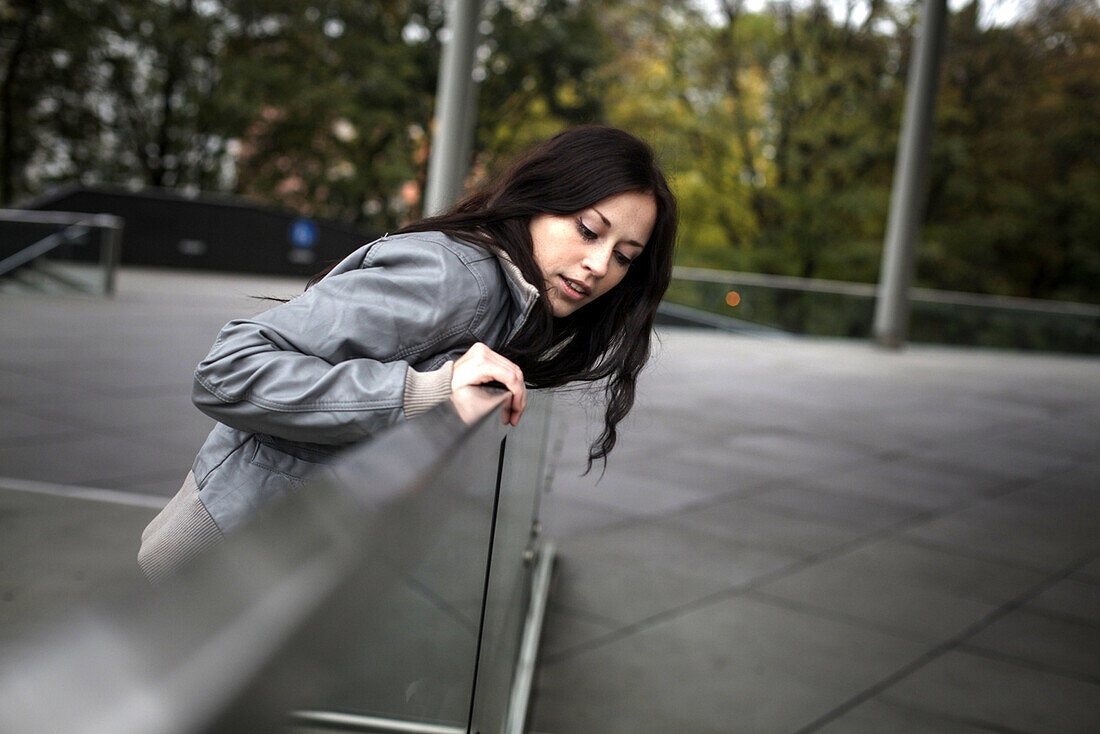 Young woman looking over a balustrade, Munich, Bavaria, Germany