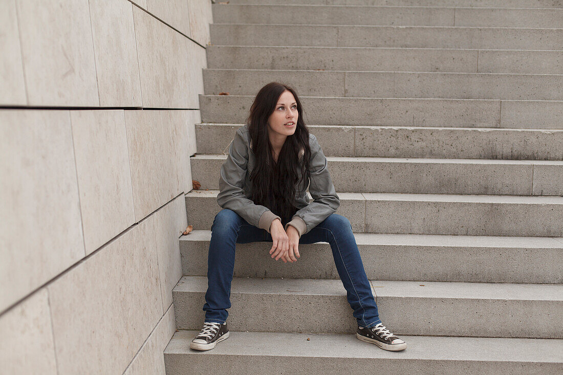 Young woman sitting on a staircase, Munich, Bavaria, Germany