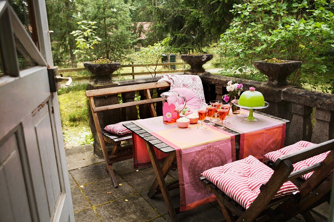 A view onto a laid terrace table with wooden chairs on an old stone patio