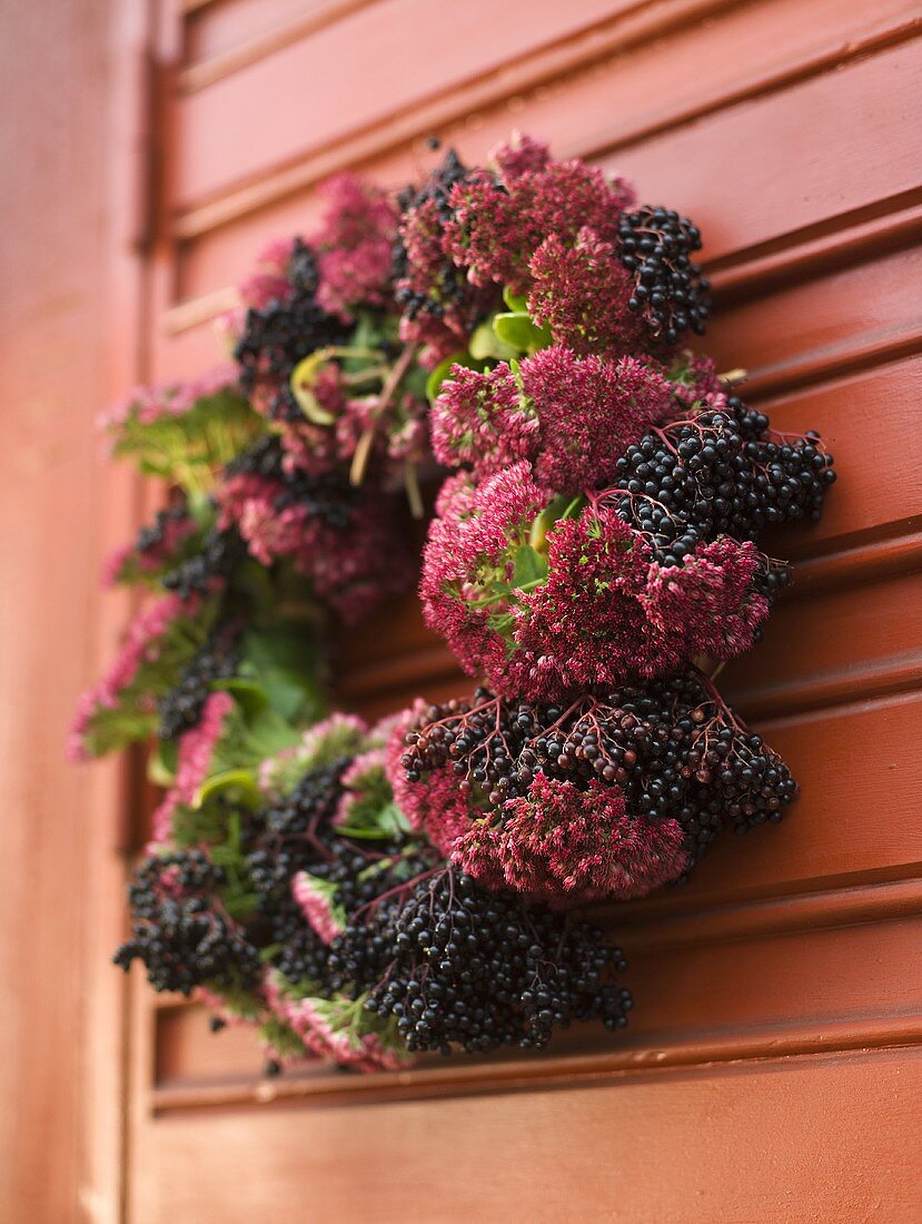 A wreath of red and blue berries on a wooden red door