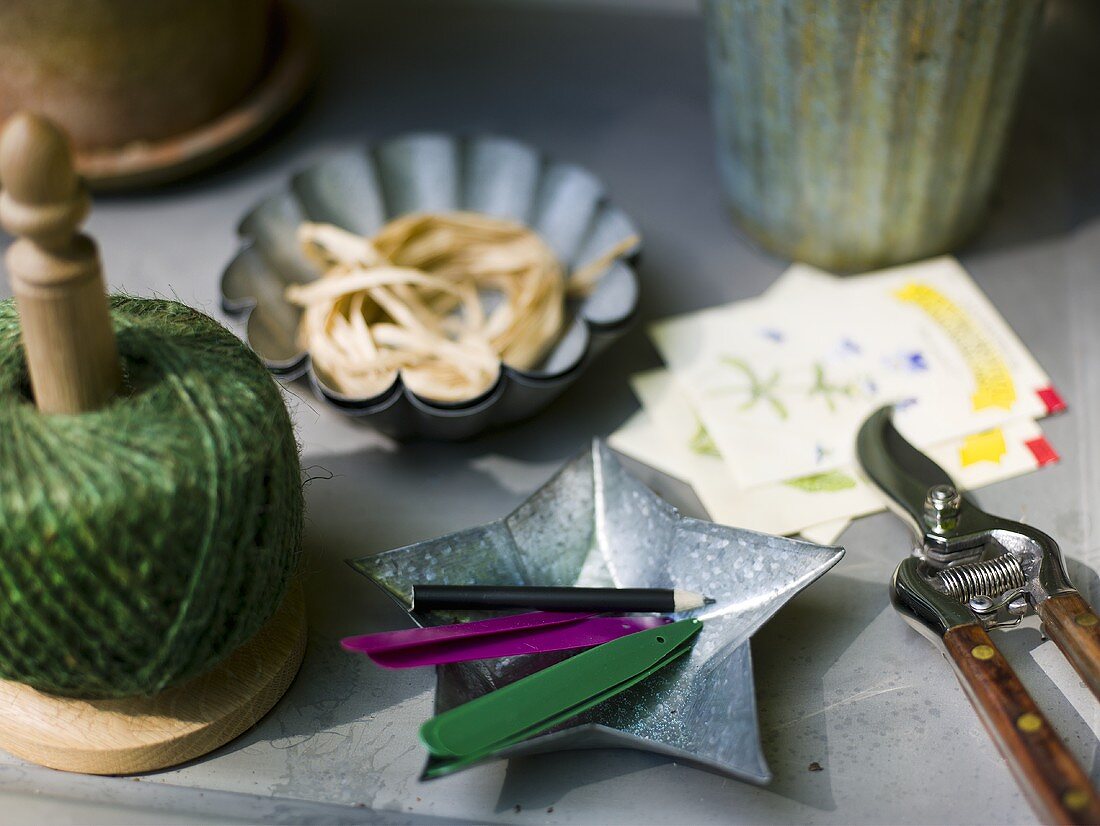A roll of twine and a bowl with pencil and craft untensils on a table
