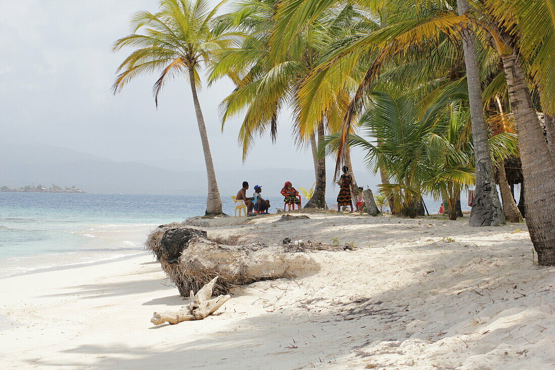 Group of Kuna Indians sitting in the palm grove on the sandy beach of San Blas Islands, Panama, Central America.
