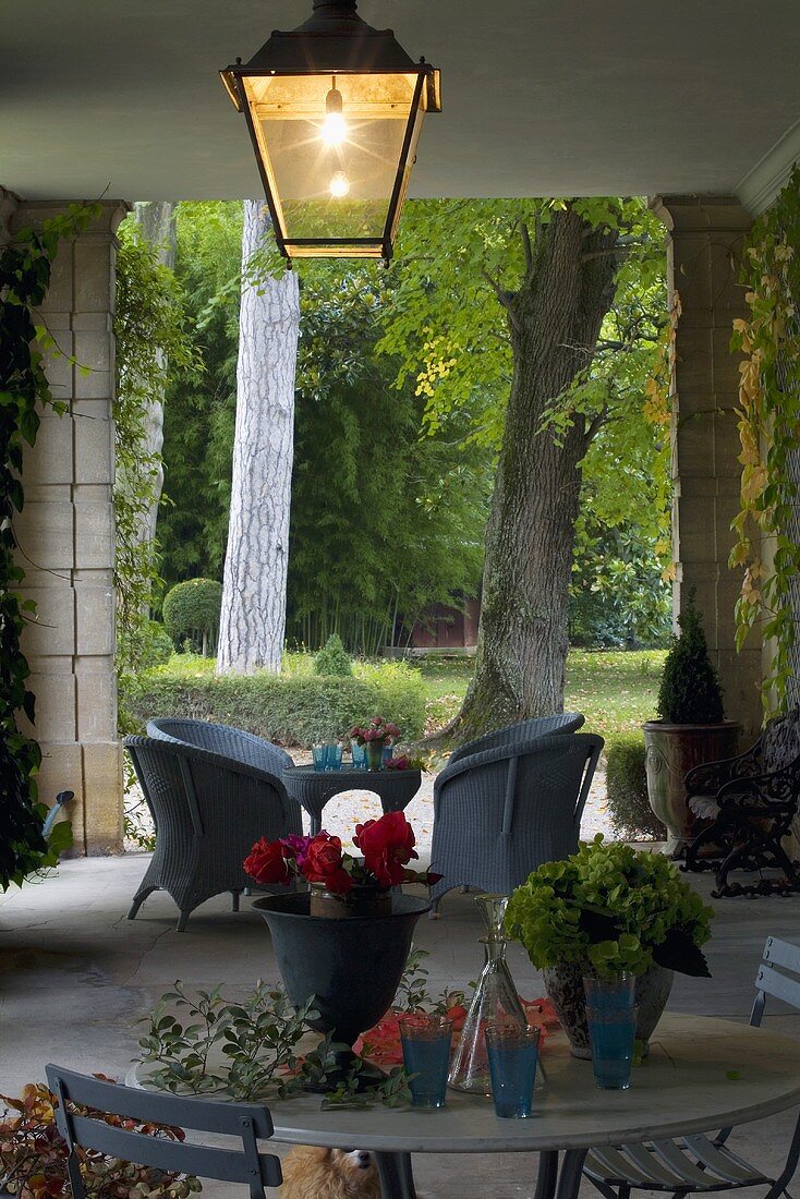 Ceiling lighting in a loggia with wicker furniture and a view of the garden