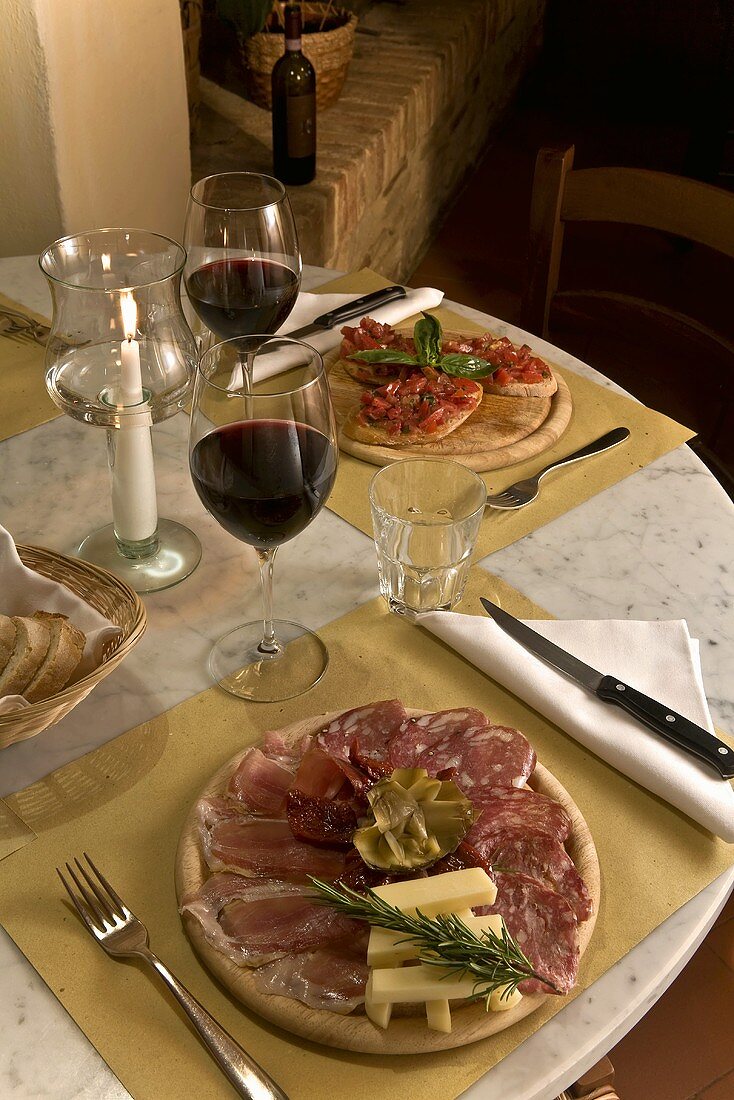 A table laid with an antipasto platter, red wine and bruschetta