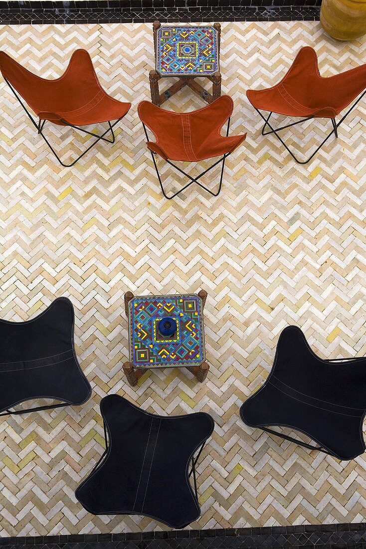 View of a classic chairs with brown and black fabric with oriental side tables and tiles in a herring bone pattern