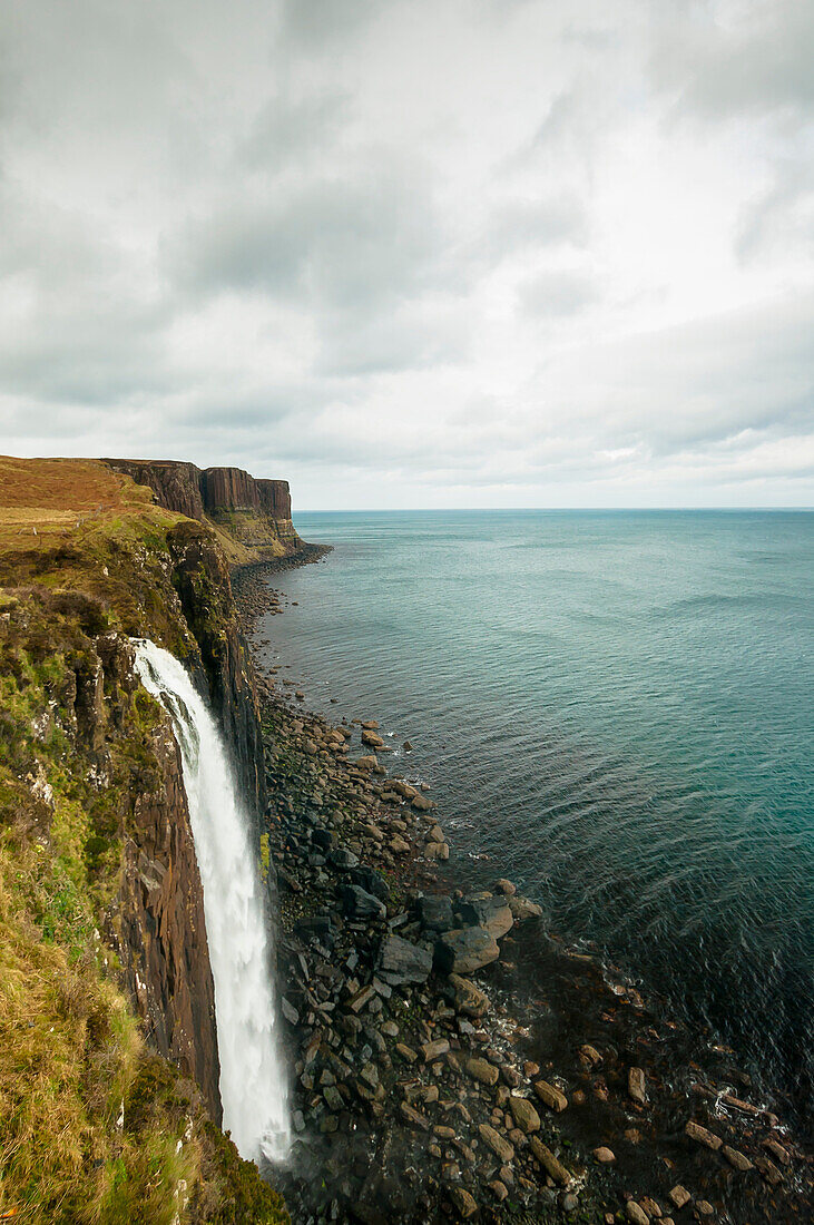 60m tall Mealt Waterfall and the Atlantic Ocean/Sound of Rasaay with red cliffs of Kilt Rock in the background, Trotternish, Isle of Skye, Scotland
