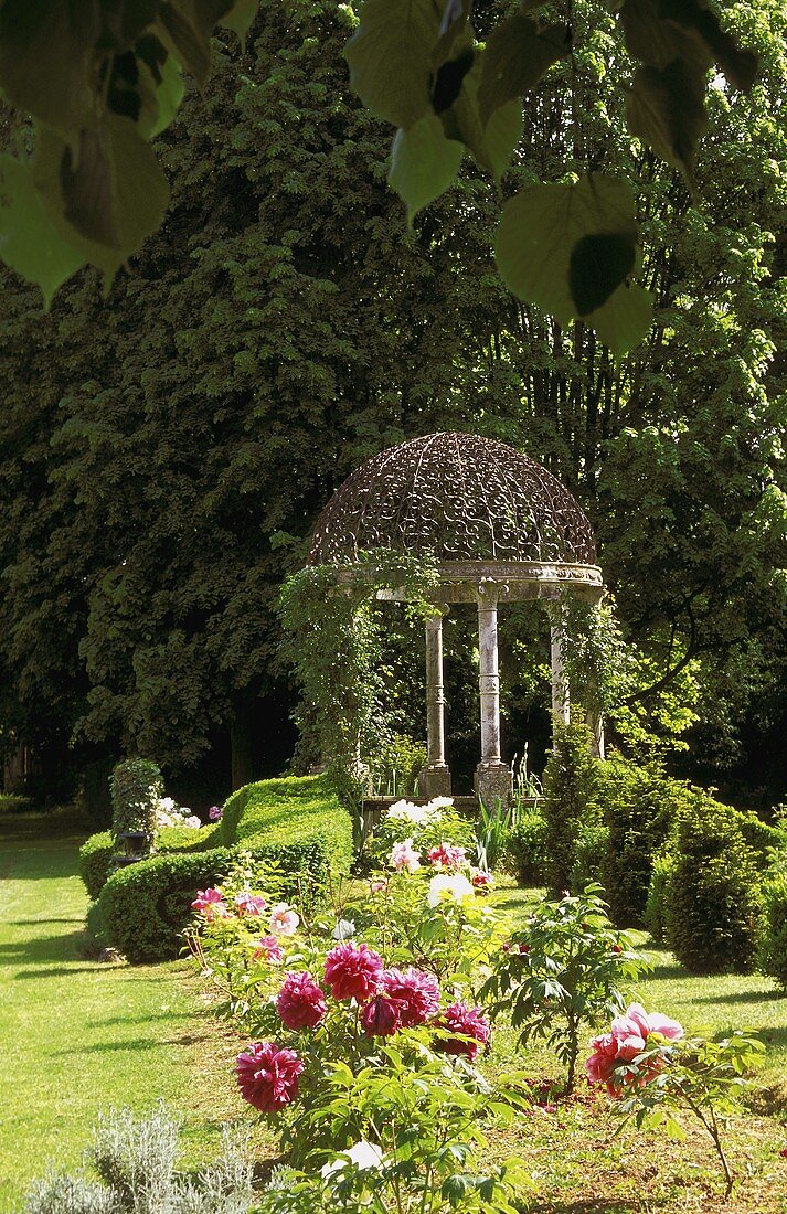 Garden pavilion with columns in a blooming garden