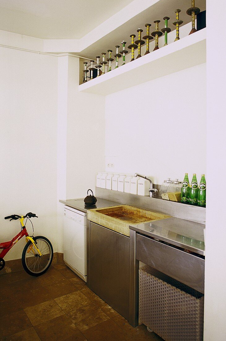 Corner of a kitchen with stainless steel built-ins and a bricked shelf with a collection of candlesticks