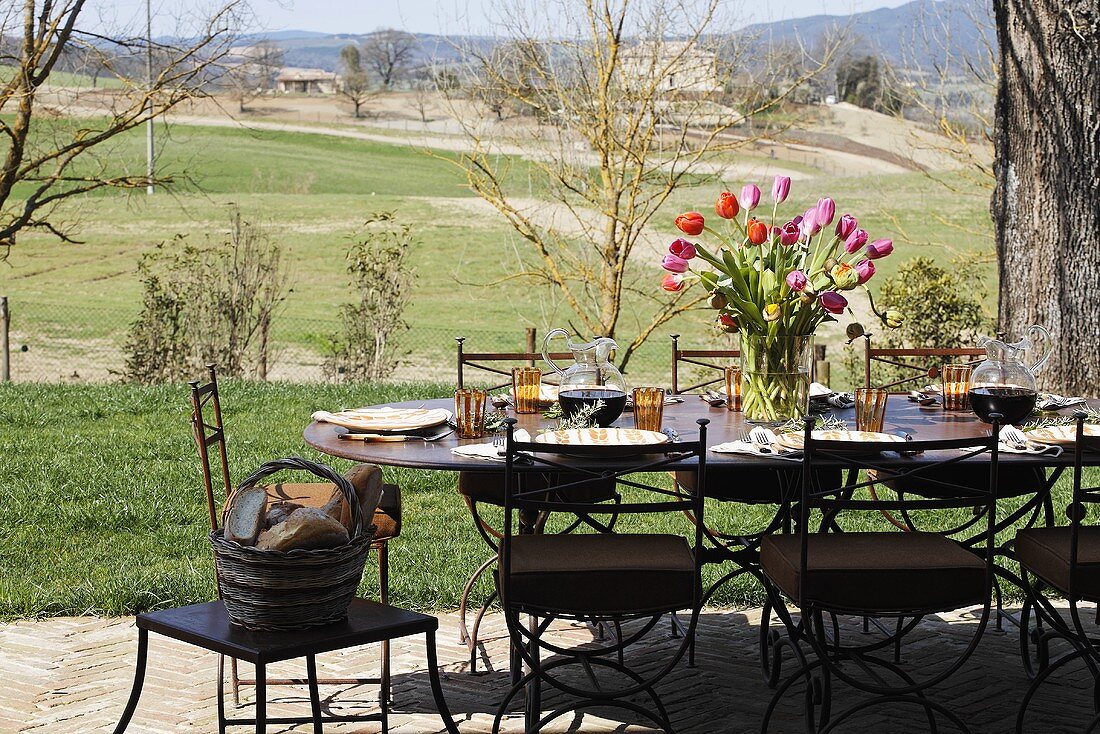 A table laid on a terrace with a bunch of tulips and view over the Mediterranean landscape