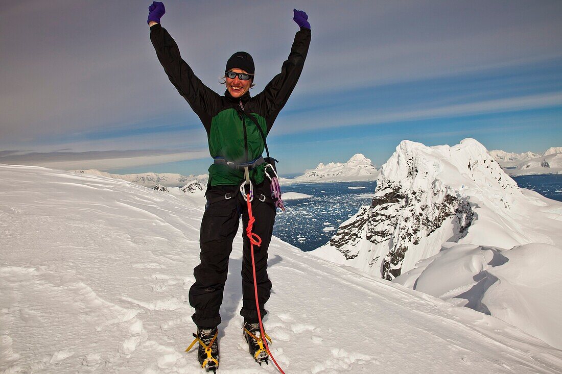 Female climber happy to have reached summit Mt Don Roberts, Lemaire Island, above Paradise Bay, Antarctic Peninsula.