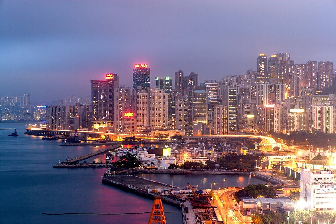 Skyline of Hong Kong Island with commercial and residential buildings with a conjested road in the foreground at dusk, China, East Asia