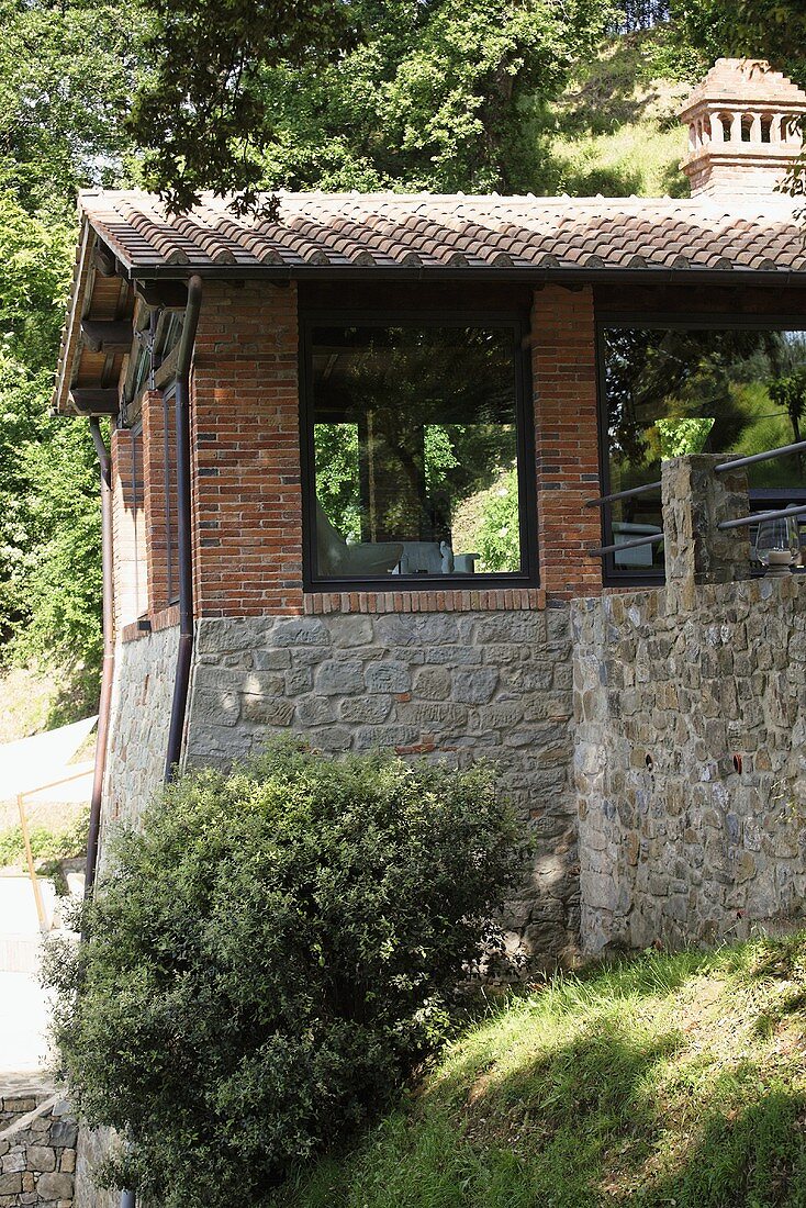 Renoviertes Landhaus mit Ziegelfassade und raumhohen Fenstern am Hang