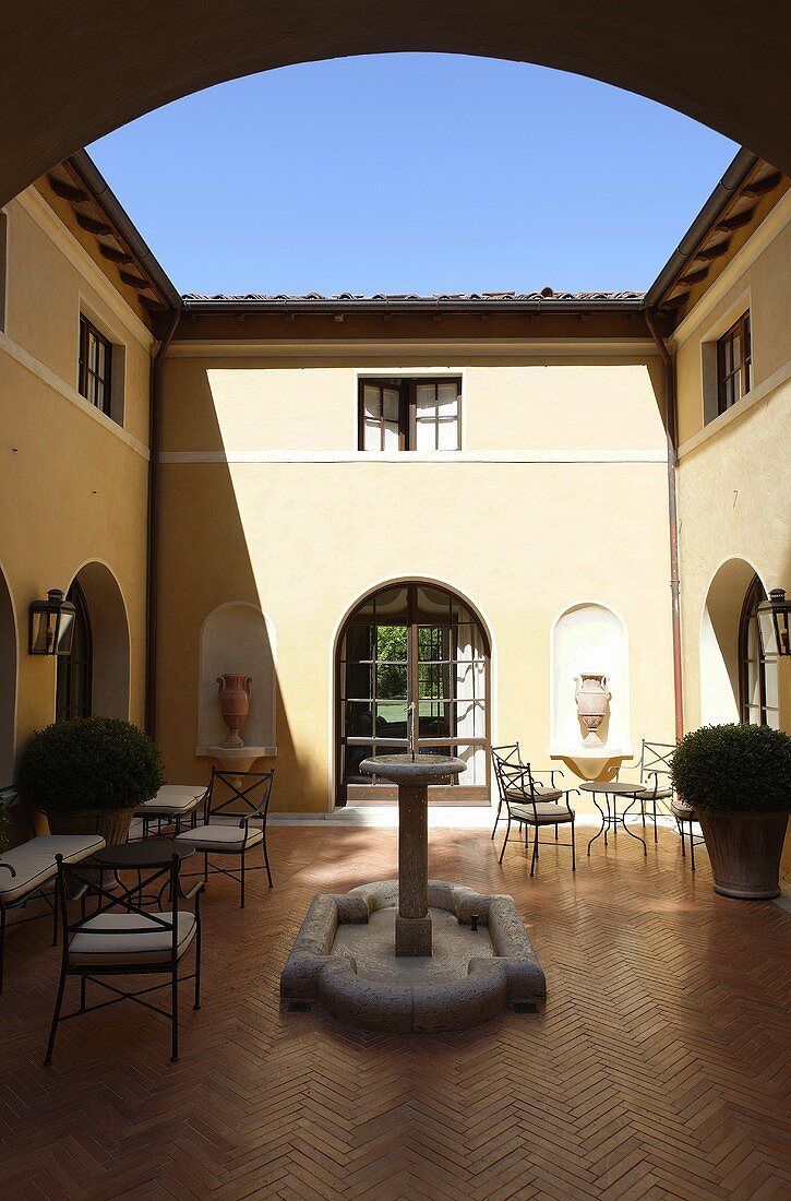 The sunny Mediterranean courtyard of a villa with a stone fountain