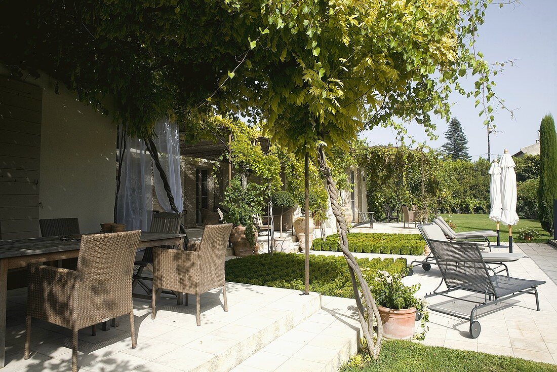 Sunny feeling - country home terrace made of light stone with wicker chairs and lounge chairs