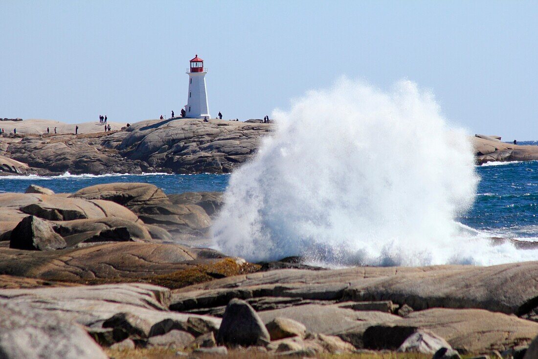 Large waves breaking on the rocks at Peggys Cove in Nova Scotia showing the lighthouse