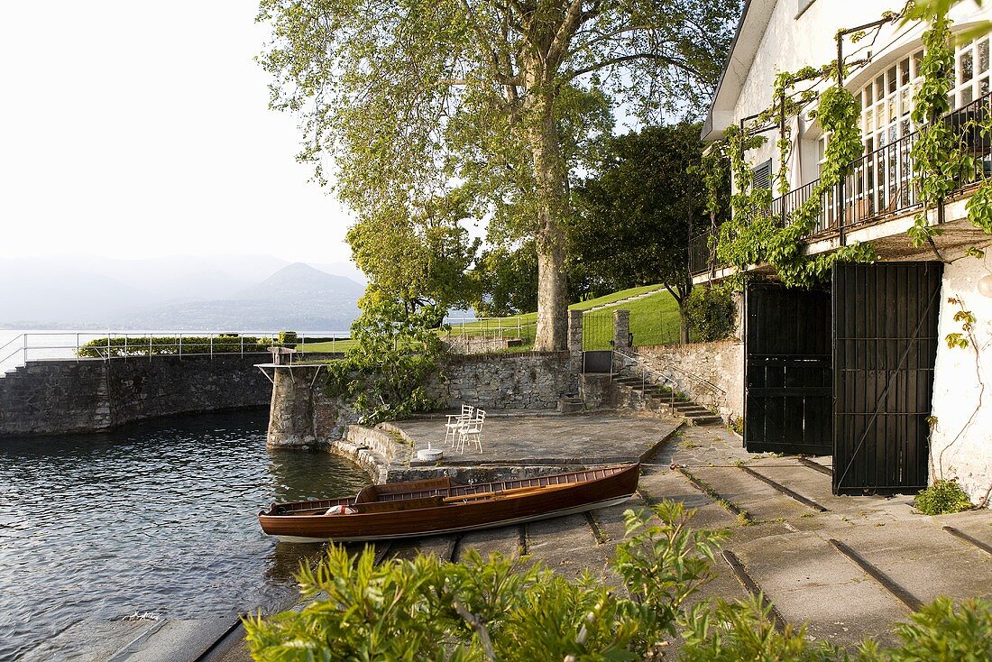 Wooden boat at a private dock in front of a home with a built in boat garage