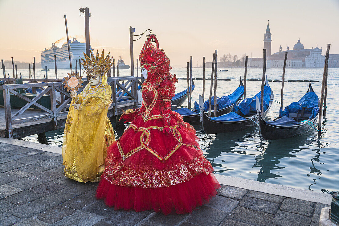 Two masked women at the carnival in Venice with gondolas in the background, Italy, Europe