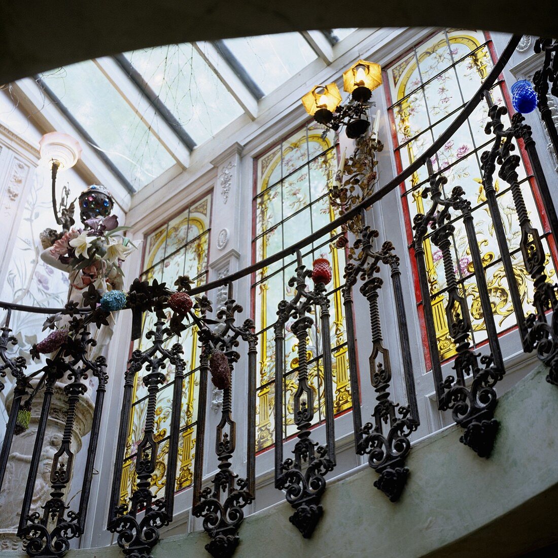 A stairway in a Baroque castle with a view through the banister onto floor-to-ceiling windows