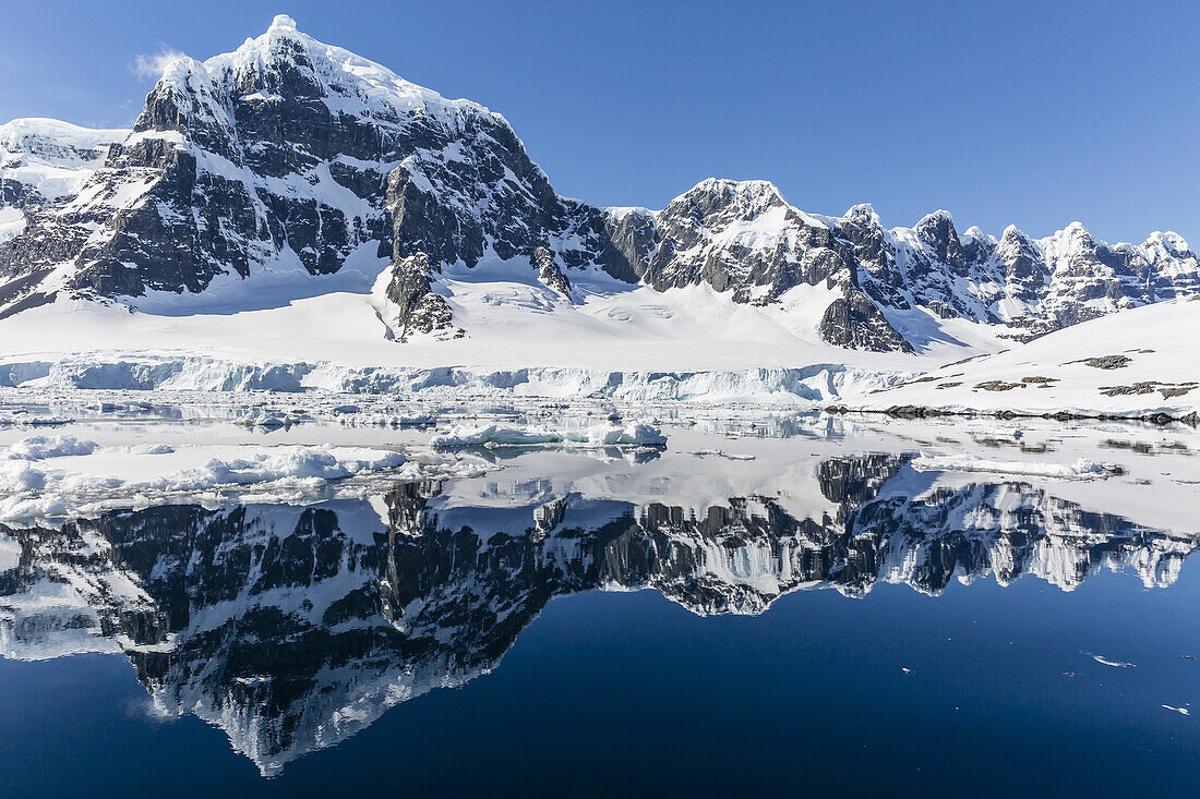 Snow-capped mountains reflected in the Neumayer Channel near Port Lockroy, Antarctica.