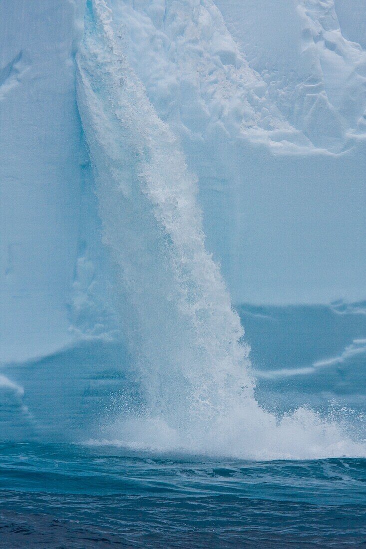 A huge tabular iceberg encountered in the Drake Passage approaching the Antarctic Peninsula during the summer months  Meltwater from within the iceberg has caused this waterfall  More icebergs are being created as global warming is causing the breakup of 