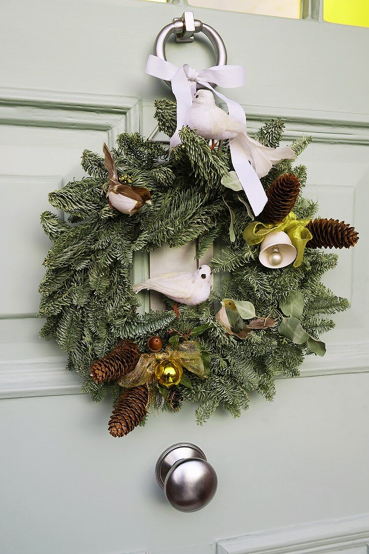 A Christmas wreath on a white front door with pine sprigs and animal figurines