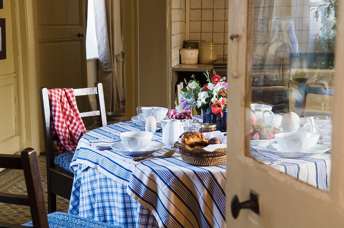 A view through an open door onto a breakfast table in the kitchen of a country house