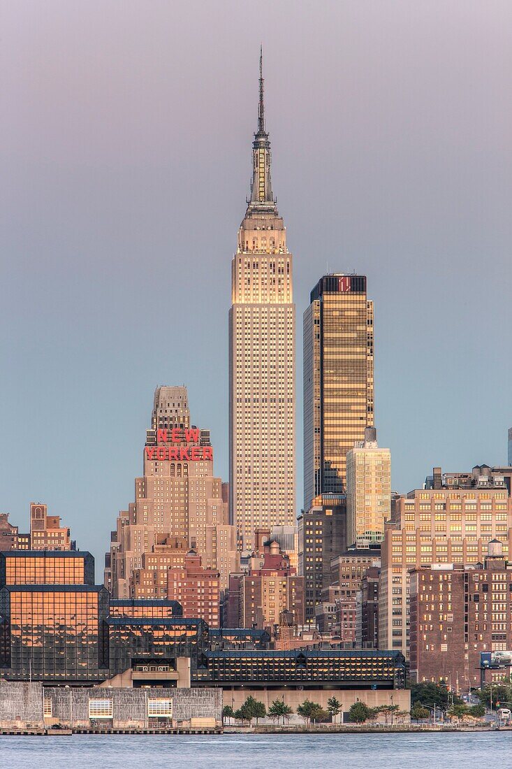 The Empire State Building and Manhattan skyline at dusk, with the orange glow of the western sky reflected in the windows, as seen from Weehawken, New Jersey, USA