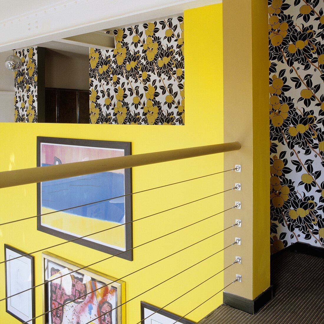 A gallery with view onto a yellow wall and a wall with a floral patterned wallpaper