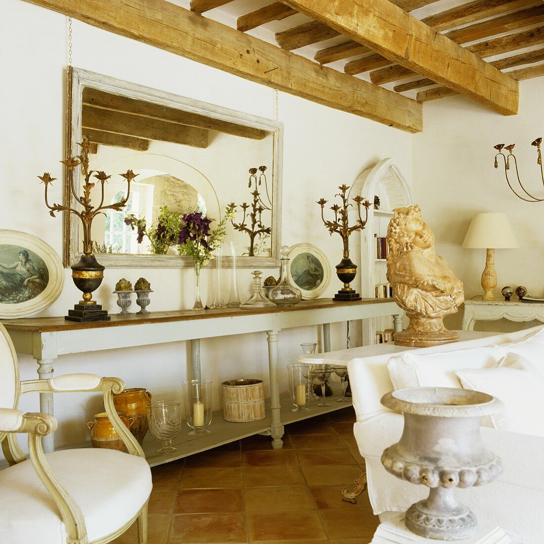 Living room with rustic wooden beams and long half high wall shelf with candelabras in front of a mirror