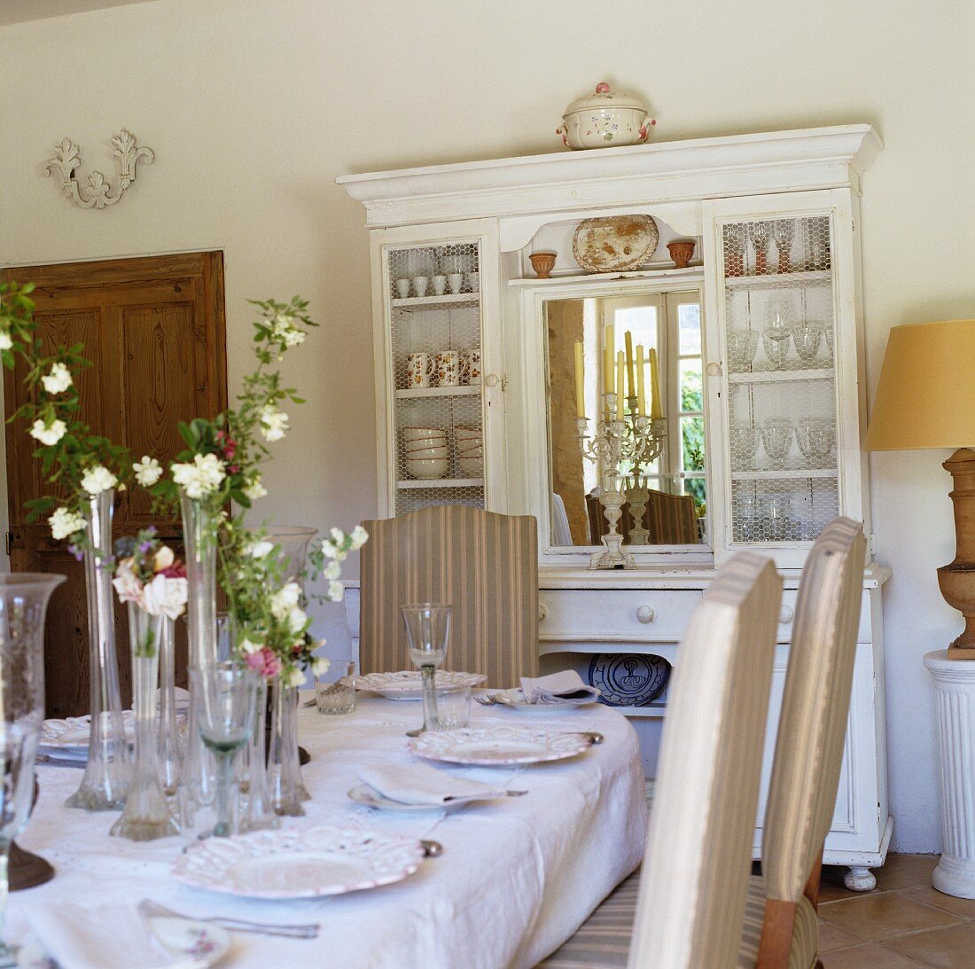 A laid table and a white crockery cabinet with a mirror in a Mediterranean dining room