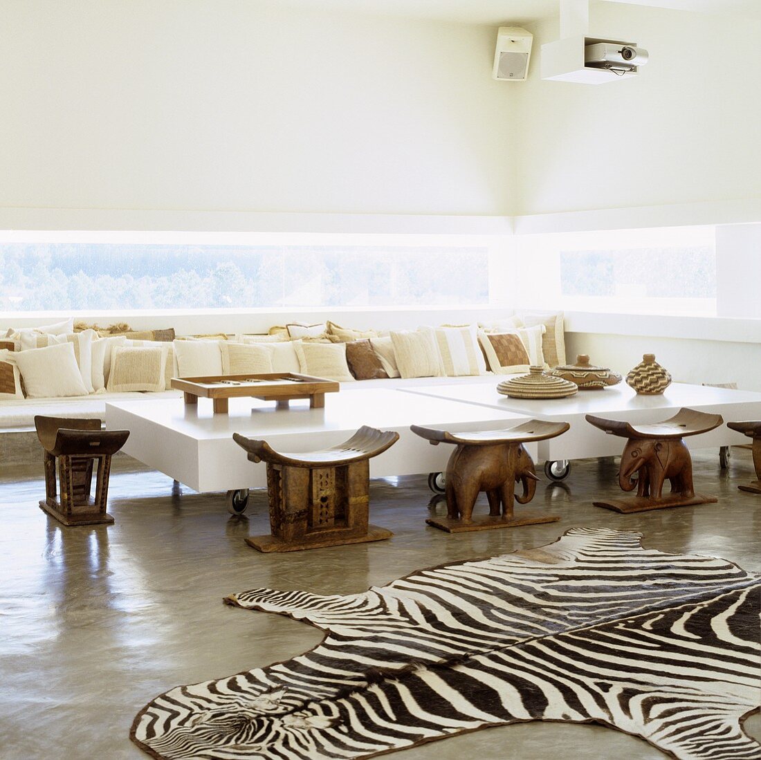 A Mediterranean designer house - a zebra rug in front of ethnic wooden stools and a designer coffee table